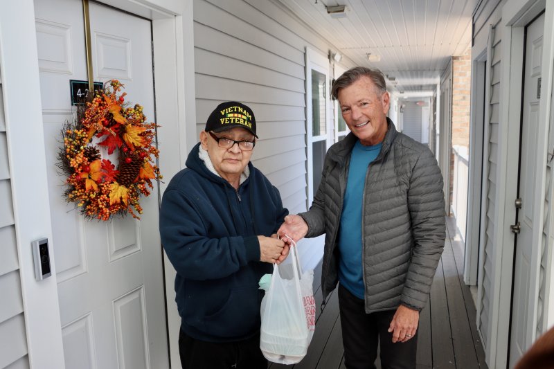 Tito Martinez, left, receives his Friday food delivery from Richard Chambers, a Meals on Wheels volunteer driver. Martinez was one of 14 clients on Chambers’ route outside Lewes and Rehoboth Beach. The Lewes group of volunteers has 19 routes in the area. BILL SHULL PHOTOS